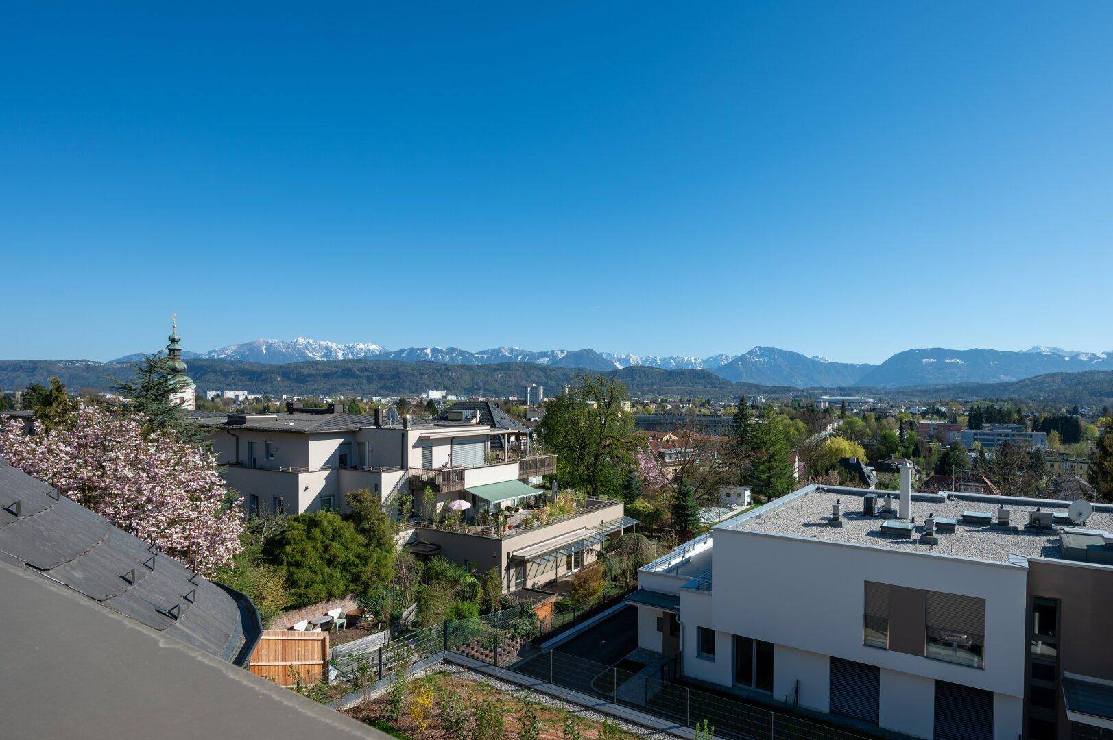 Weitläufiger Blick über die Stadt und die umliegende Landschaft mit schneebedeckten Bergen.