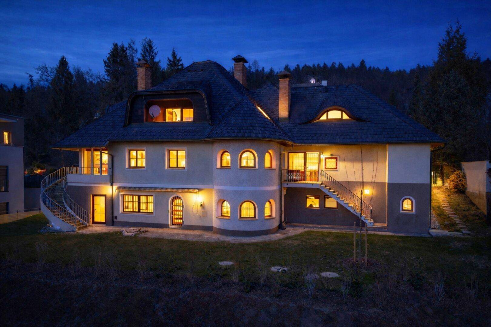 Beleuchtetes Einfamilienhaus bei Nacht, das eine warme und einladende Atmosphäre ausstrahlt.