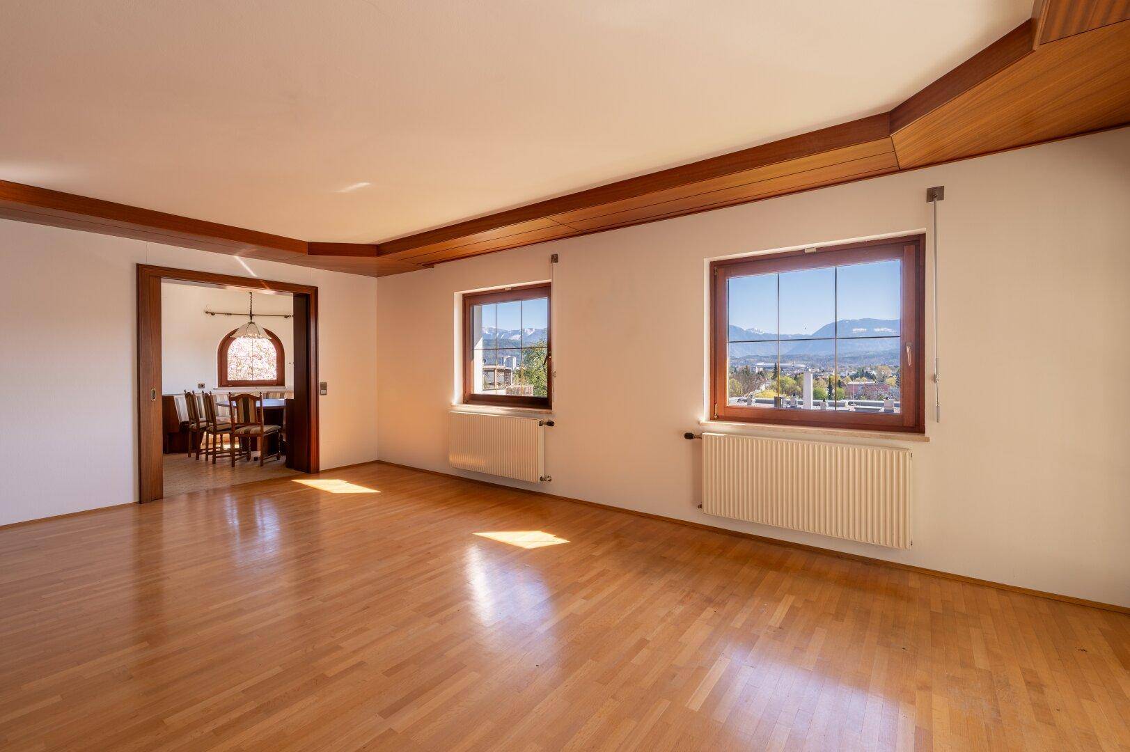Helles Wohnzimmer mit Parkettboden und Holzakzenten, bietet einen weiten Blick auf die Berge.