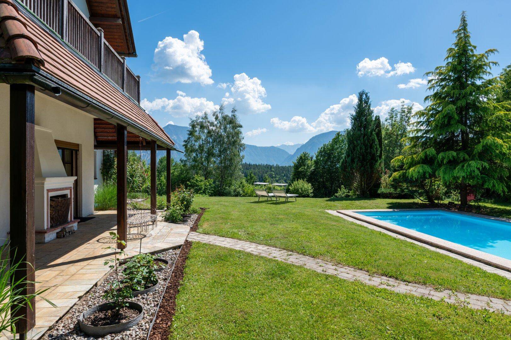 Überdachte Terrasse mit Zugang zum Garten, Pool und weitem Bergblick.
