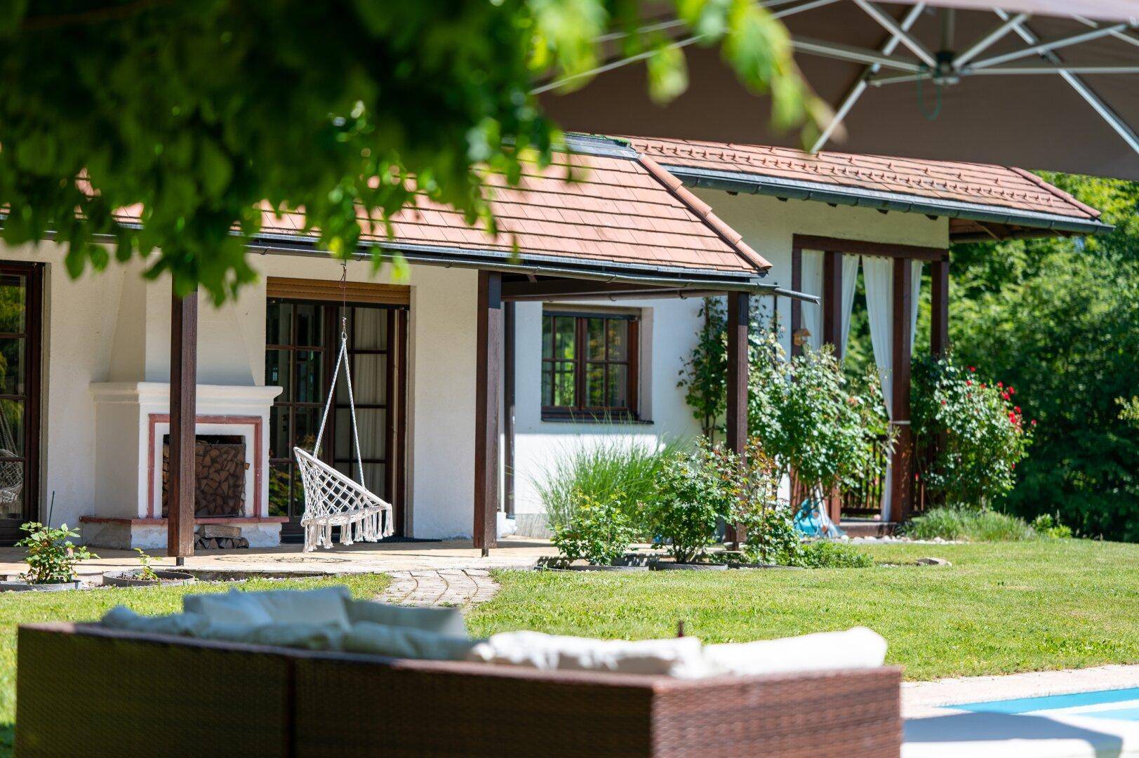Gemütliche überdachte Terrasse mit Hängesessel und Blick auf den Gartenbereich.