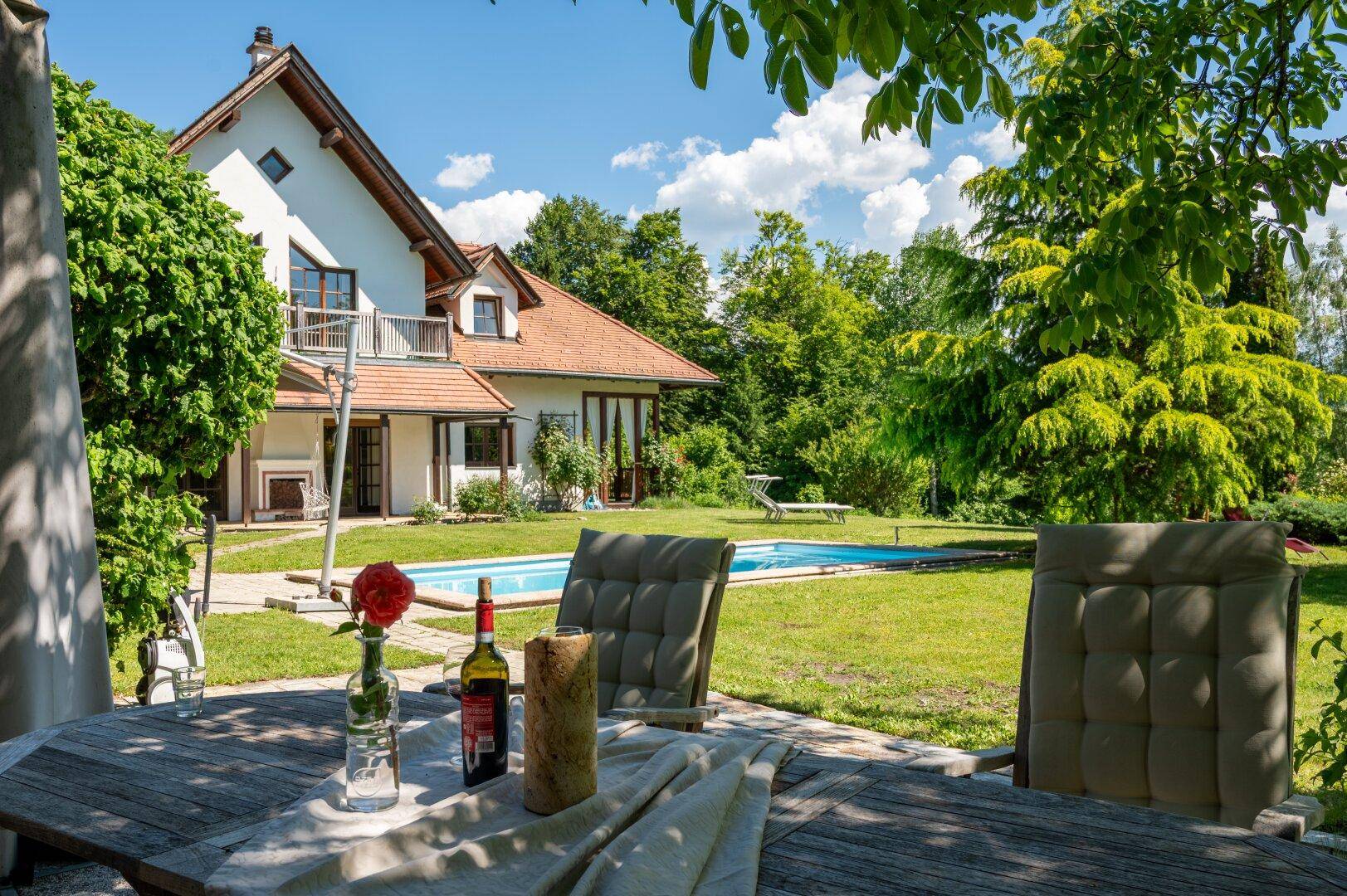 Idyllischer Garten mit Essbereich im Freien und Blick auf das Haus und den Pool.