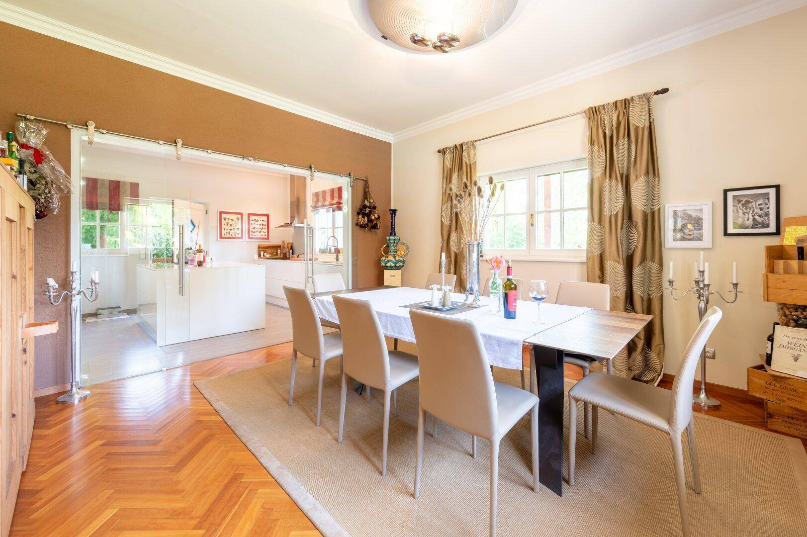 Eleganter Essbereich mit Holzboden und Glasschiebetür zur modernen Küche.