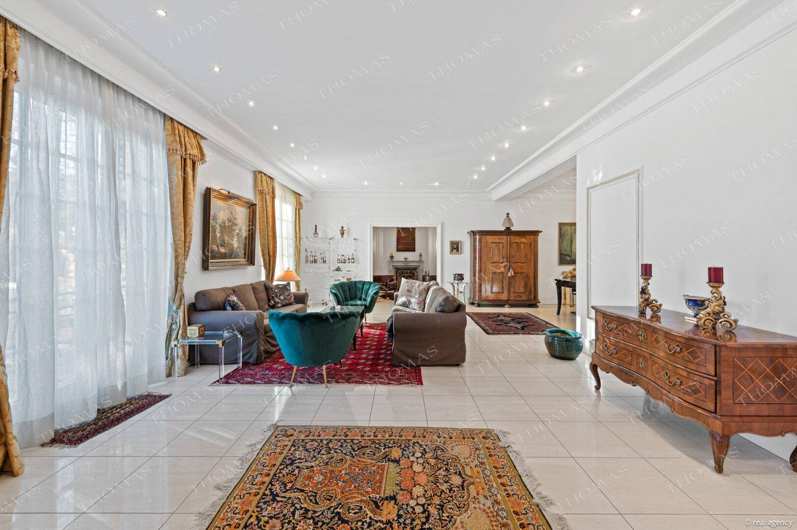 Geräumiges Wohnzimmer mit Fliesenboden, hohen Decken und klassischer Einrichtung.
