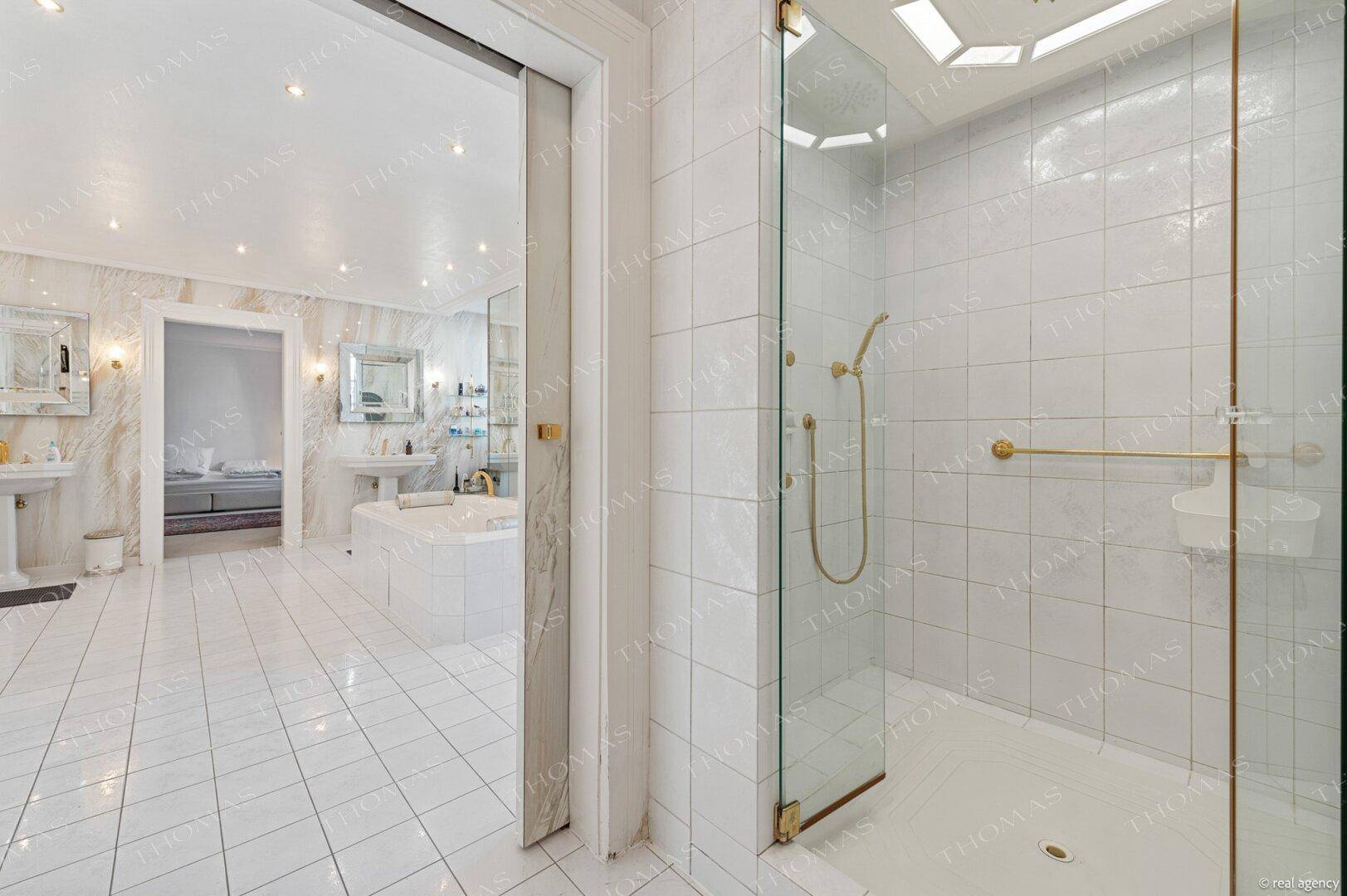 Modernes Badezimmer mit begehbarer Dusche, Fliesenboden und Blick auf die Badewanne.