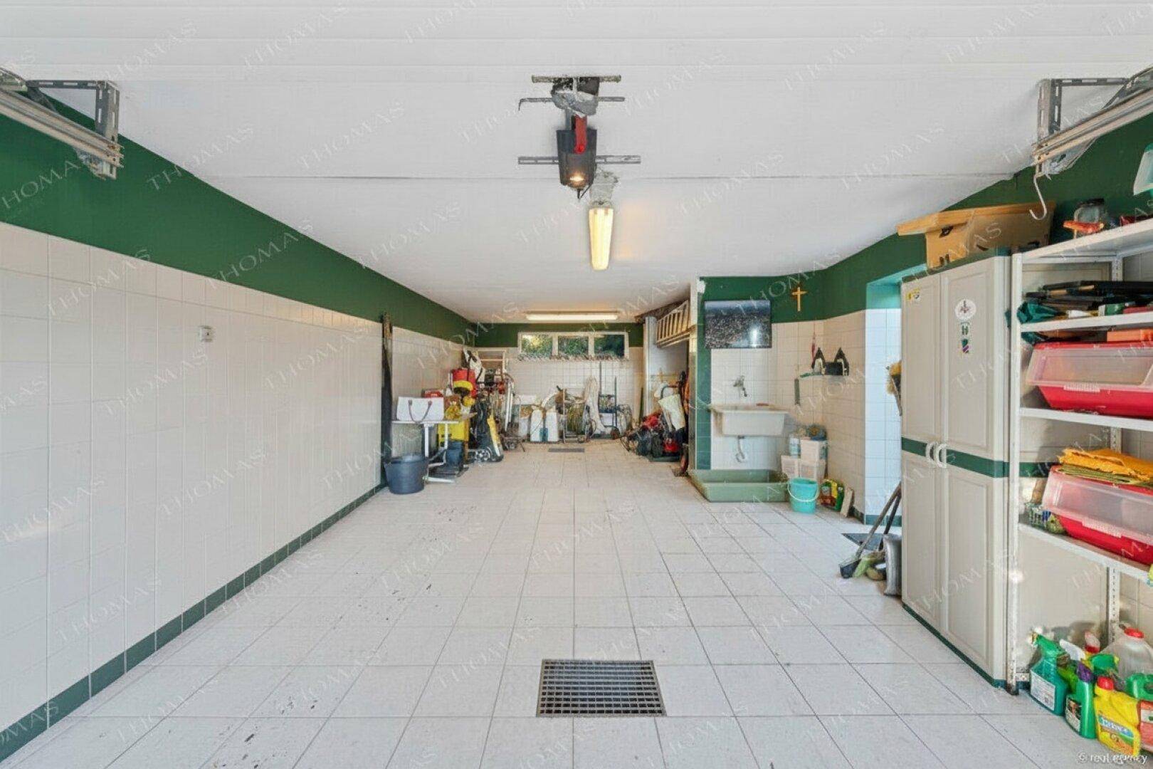 Geräumige Garage mit Fliesenboden, viel Stauraum und Arbeitsbereich.