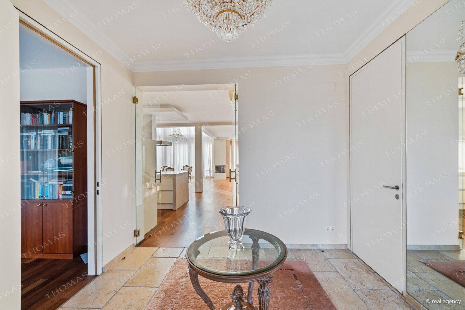 Eleganter Eingangsbereich mit Fliesenboden, Kronleuchter und offenem Zugang zu den Wohnräumen.