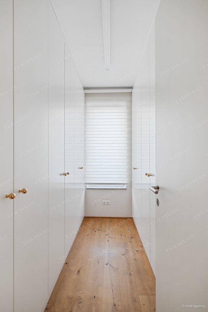 Heller Flur mit integrierten weißen Schränken und warmem Holzboden.