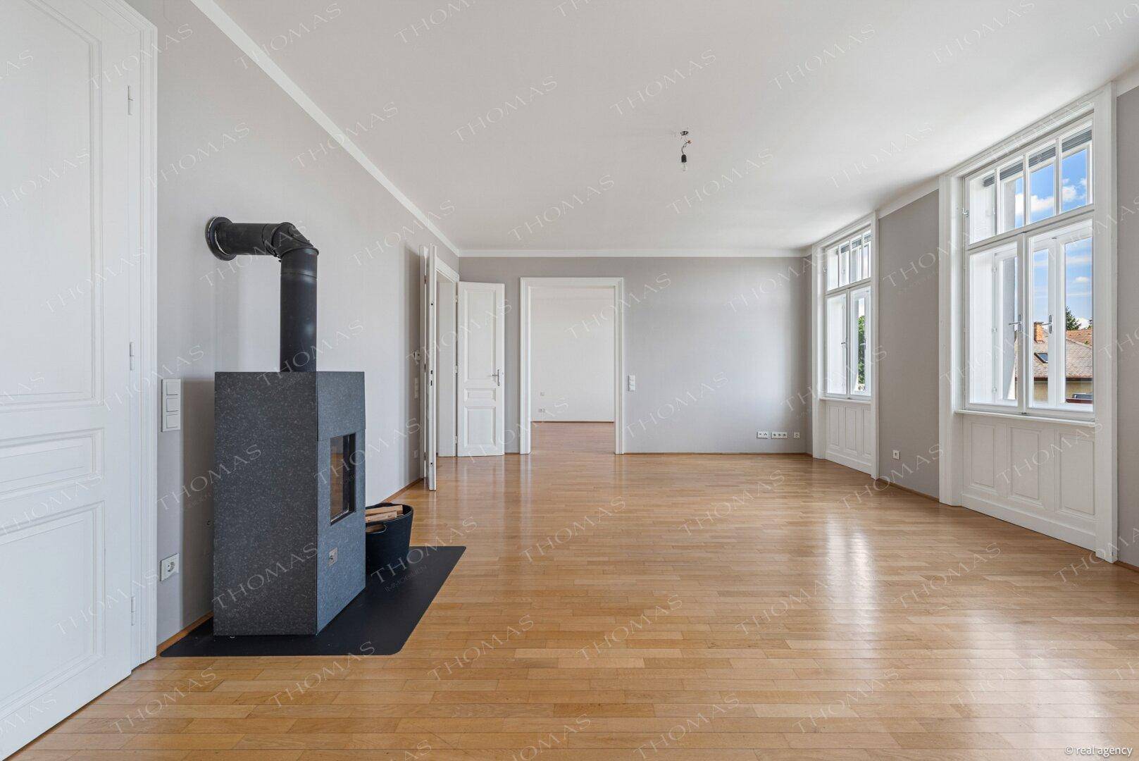 Geräumiges Wohnzimmer mit Parkettboden und einem modernen Kaminofen, bereit zur Einrichtung.