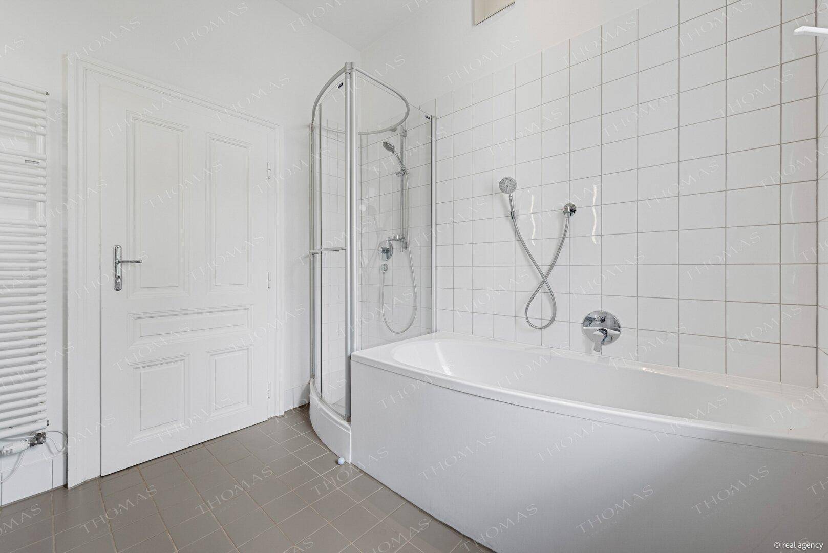 Funktionales Badezimmer mit Badewanne, Duschkabine und praktischem Handtuchheizkörper.