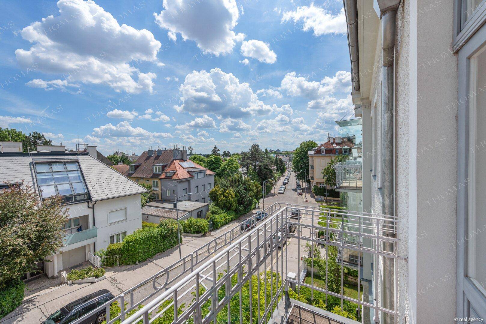 Balkon mit Blick auf eine belebte Straße und die umliegende Wohngegend unter blauem Himmel.