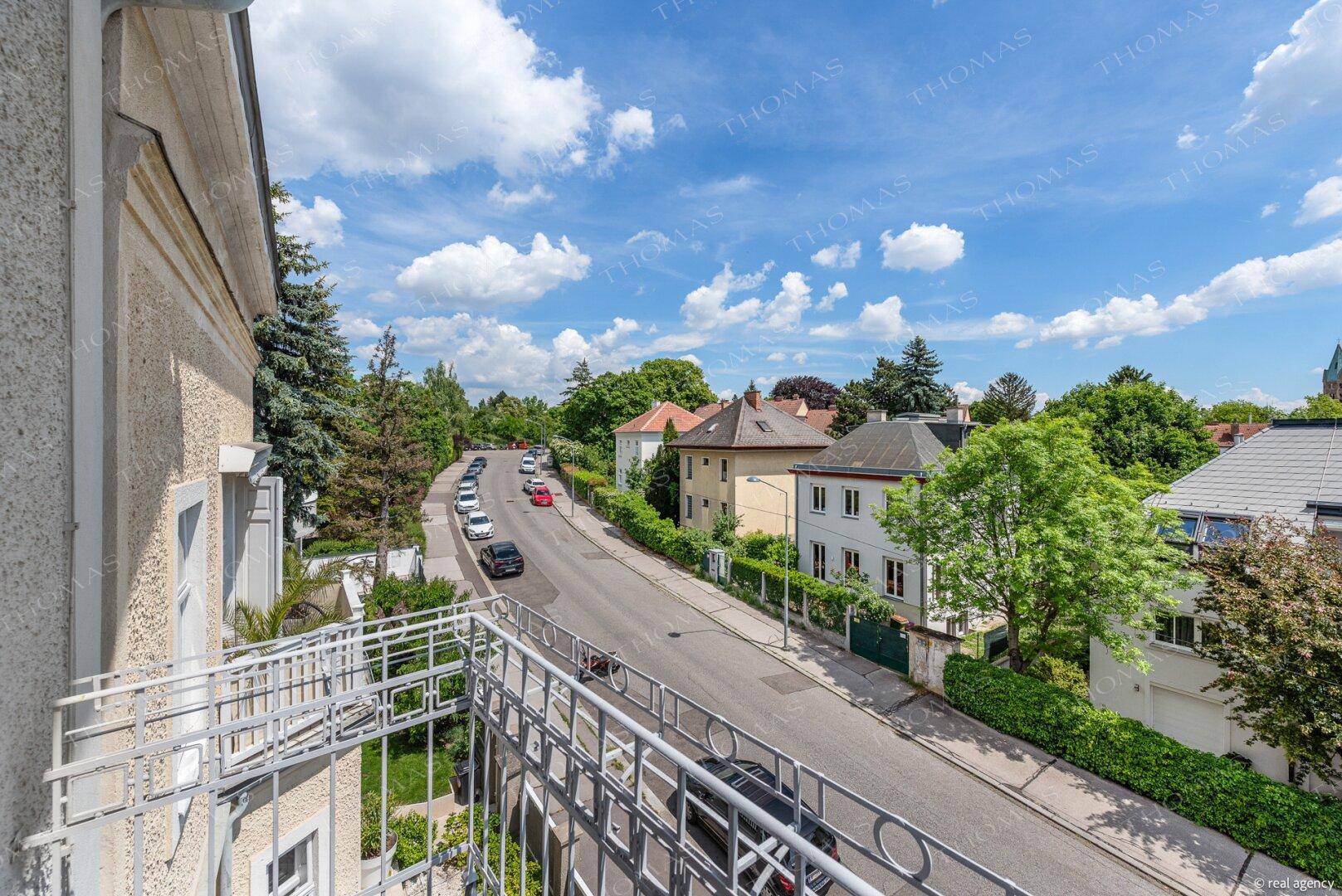 Weiter Blick vom Balkon über eine ruhige Straße und die grünen Gärten der Nachbarschaft.