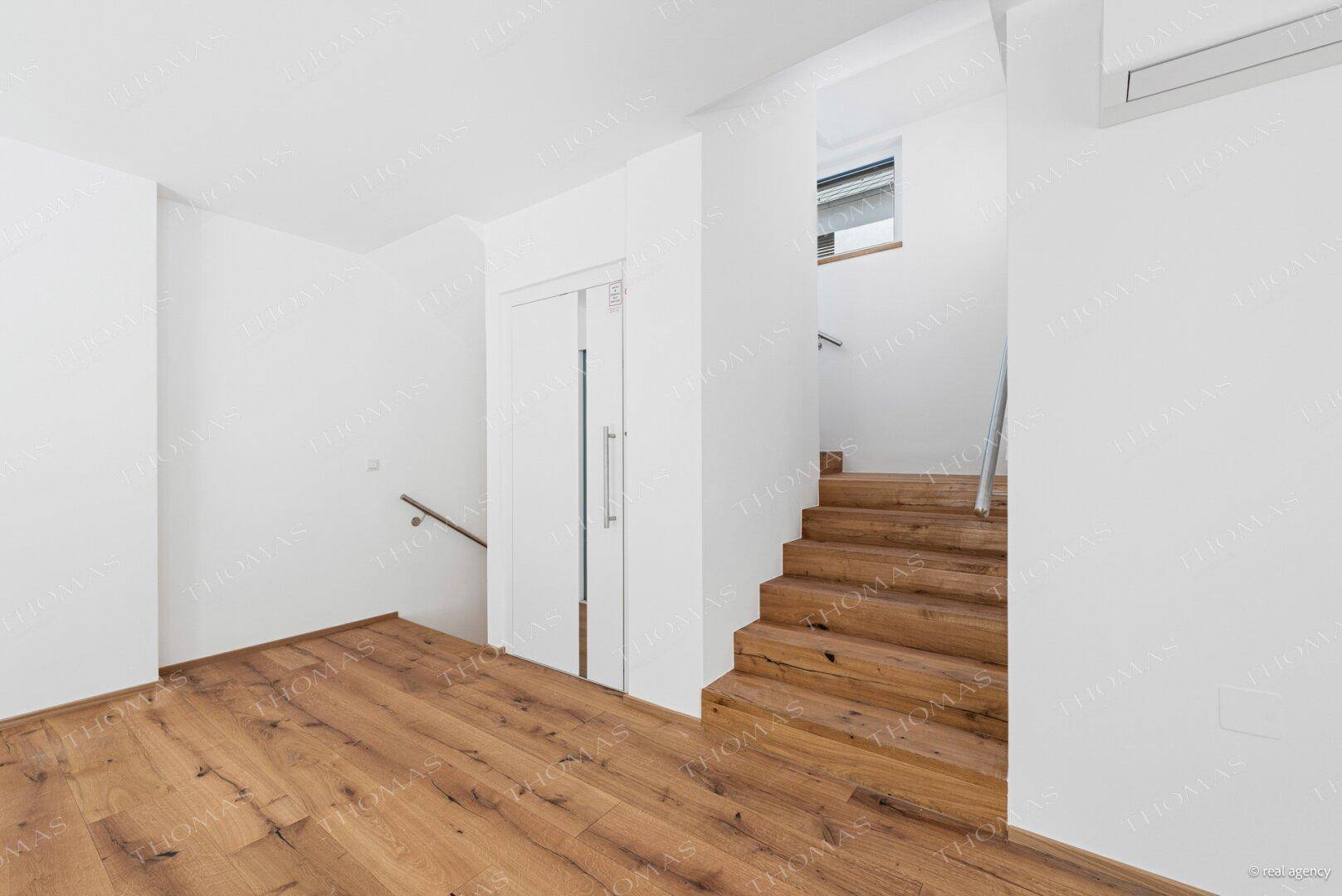Heller Flurbereich mit moderner Holztreppe und passendem Holzboden.