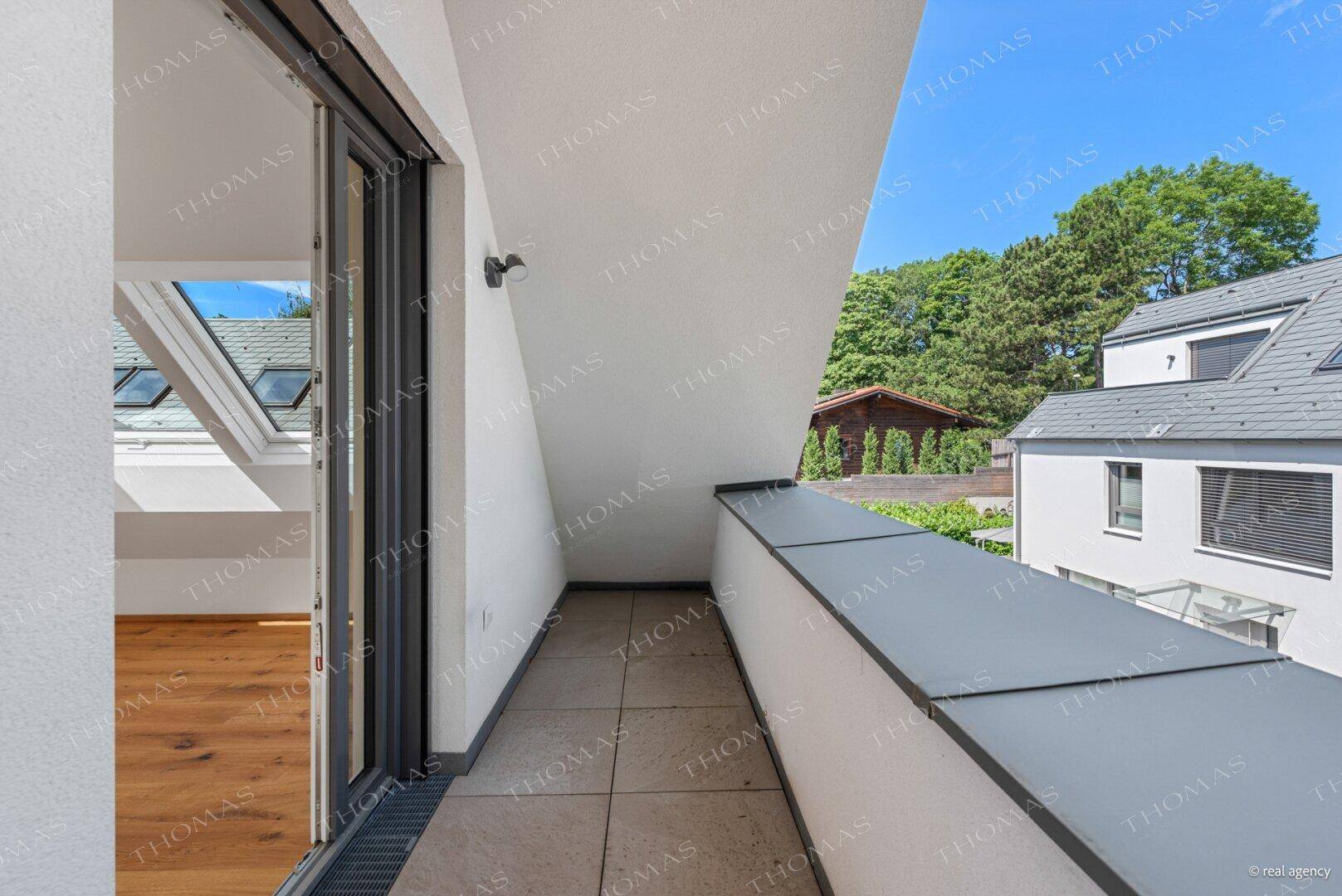 Kleiner Balkon mit Fliesenboden, zugänglich von einem Dachzimmer, mit Blick auf die Umgebung.