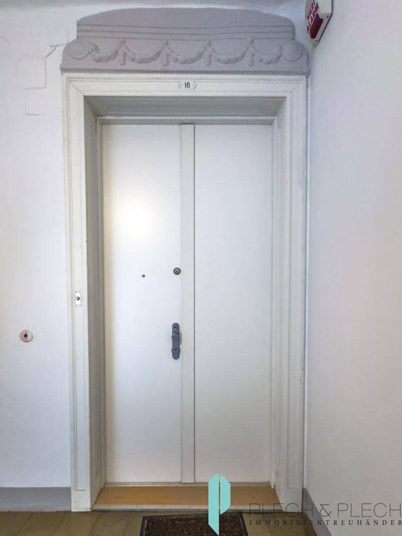 Eingangstür einer Wohnung im historischen Gebäude mit dekorativem Rahmen.