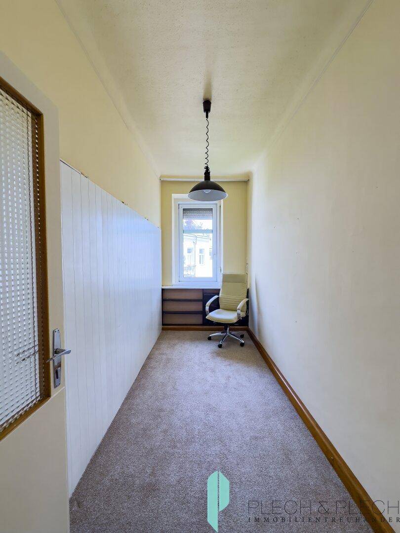 Schmaler Raum mit Teppichboden und Fenster, ideal als kleines Büro oder Arbeitszimmer.