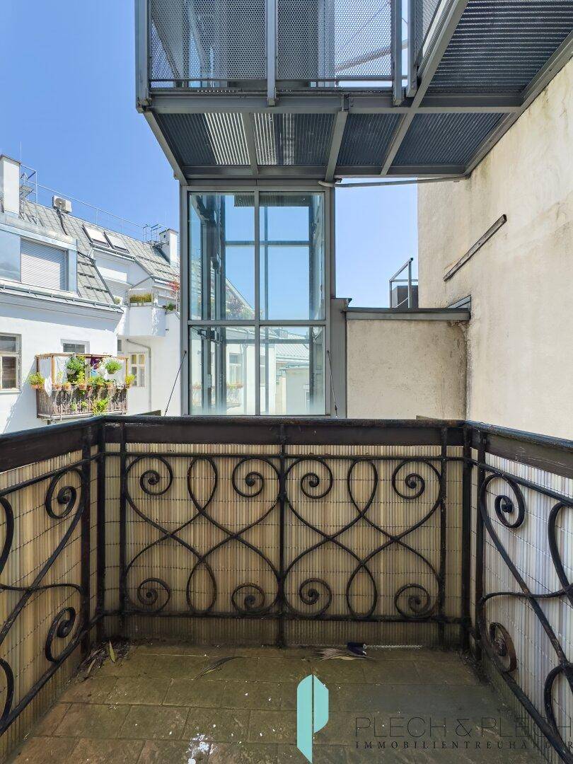 Kleiner Balkon mit schmiedeeisernem Geländer und Blick auf den Innenhof.