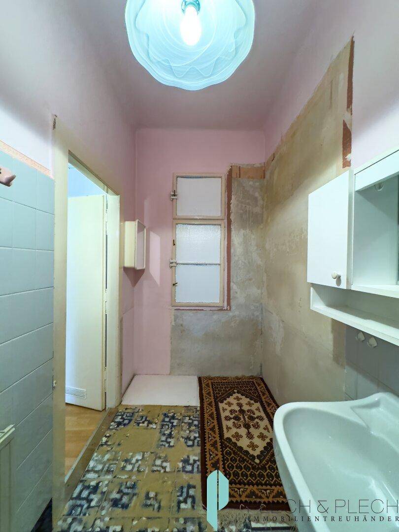 Badezimmer in Renovierung mit Fenster und Waschbecken, bereit für eine Modernisierung.