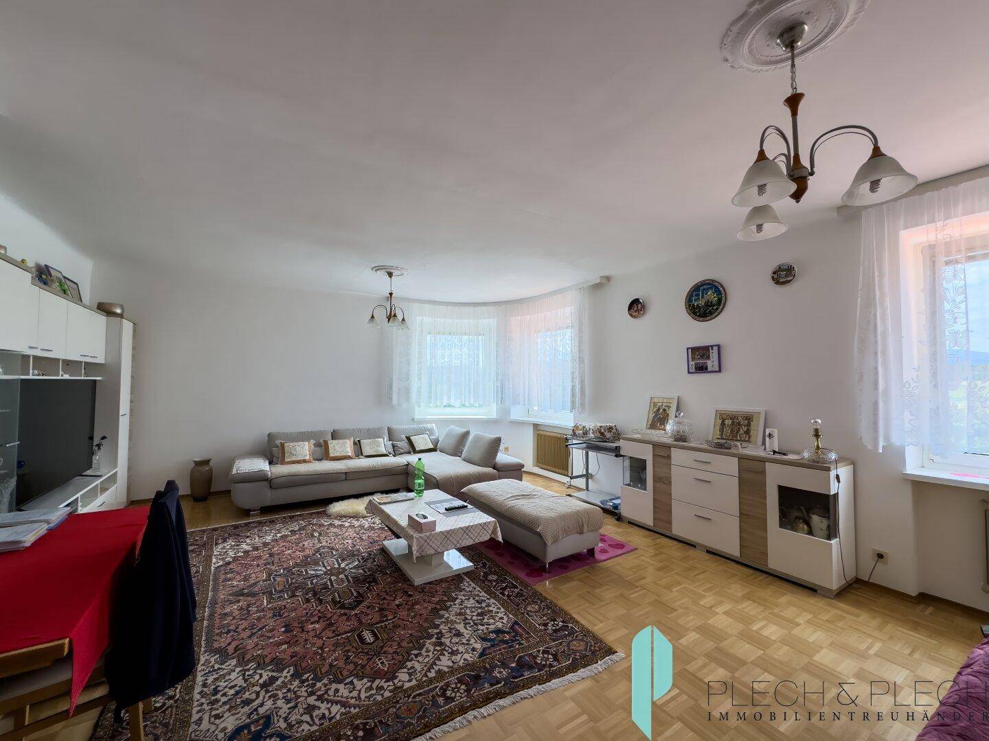 Helles Wohnzimmer mit Parkettboden, gemütlicher Sitzecke und dekorativen Elementen.