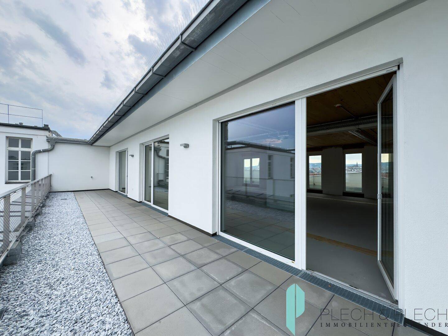 Große Dachterrasse mit Fliesenboden und Zugang zu den Innenräumen, bietet weite Ausblicke.