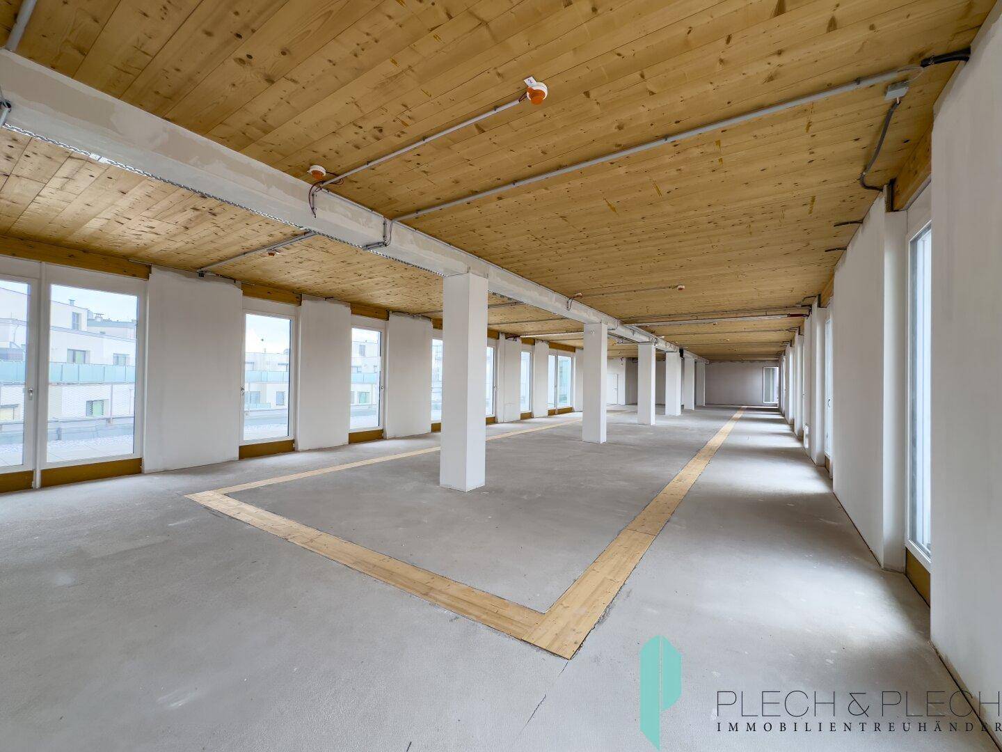 Geräumiger Gewerberaum mit hohen Decken, Betonboden und einer Reihe von Säulen, bereit für den Innenausbau.