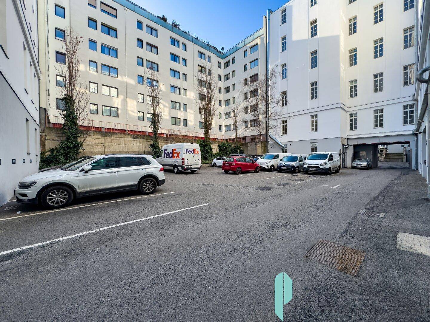 Offener Parkplatz im Innenhof des Gebäudes, mit mehreren geparkten Fahrzeugen.