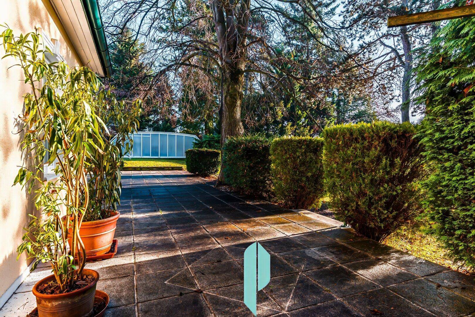 Gemütlicher Terrassenbereich mit Topfpflanzen und Blick auf den Garten.