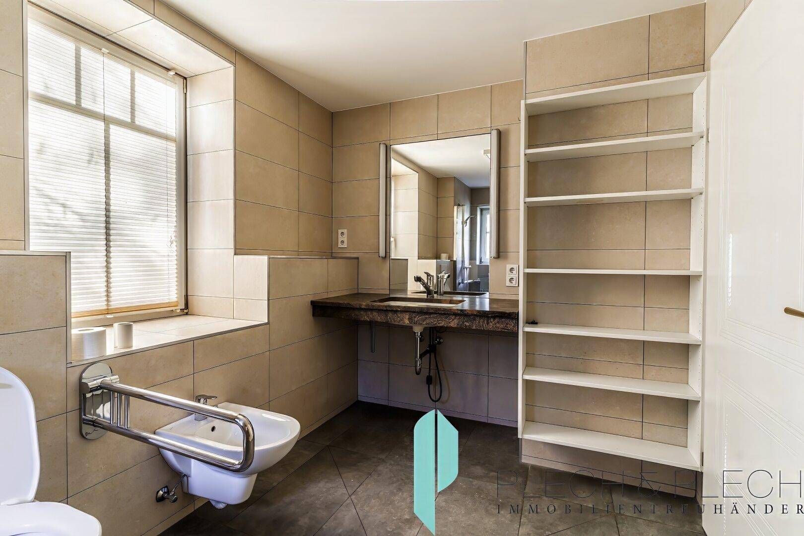 Geräumiges Badezimmer mit Fenster, Waschtisch und praktischen Regalen.