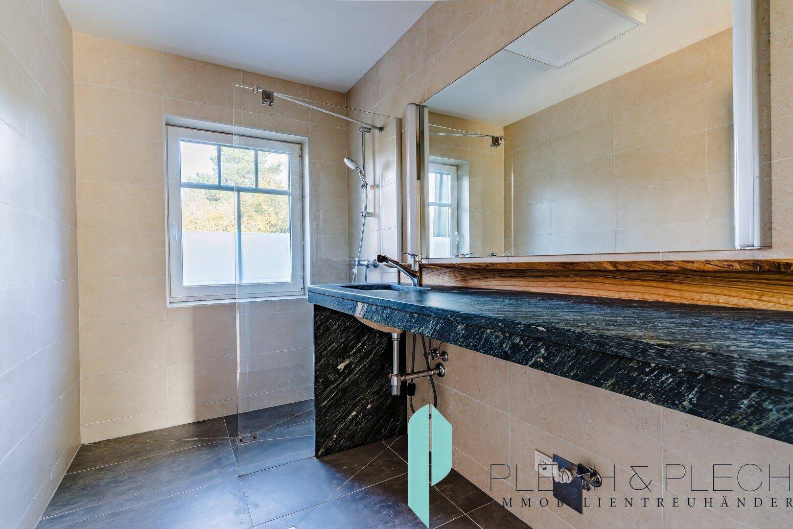 Modernes Badezimmer mit großem Waschtisch aus Naturstein und begehbarer Dusche.