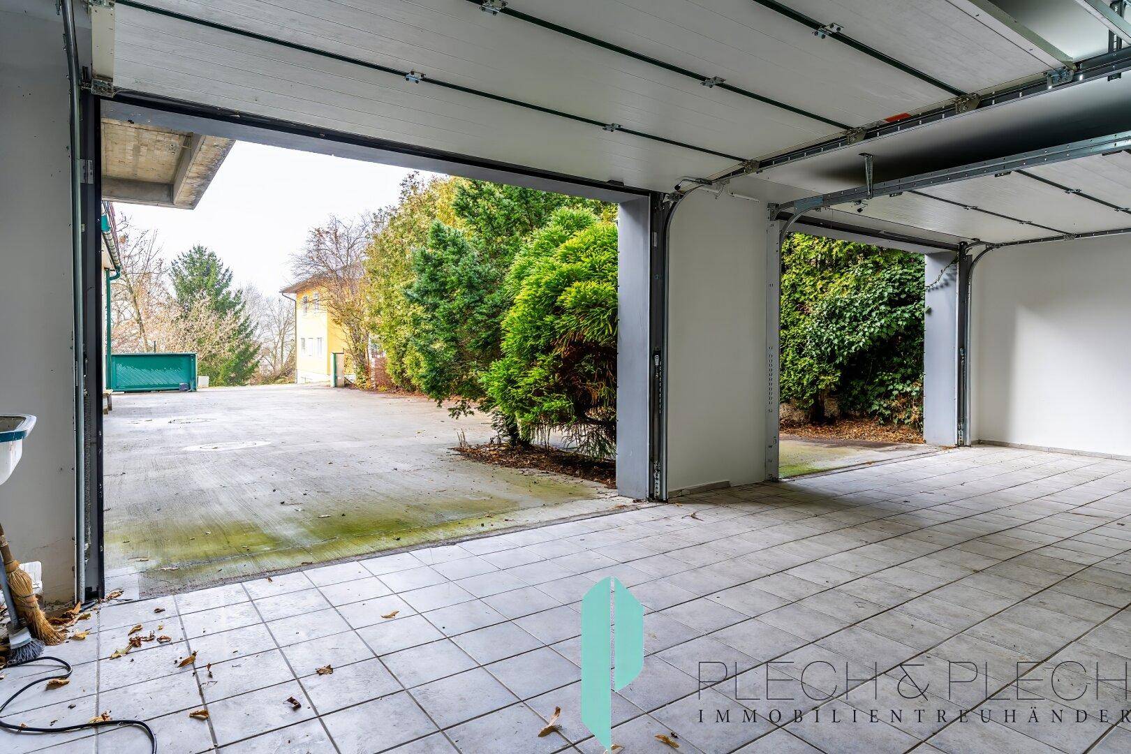 Geräumige Garage mit zwei geöffneten Toren und Fliesenboden.