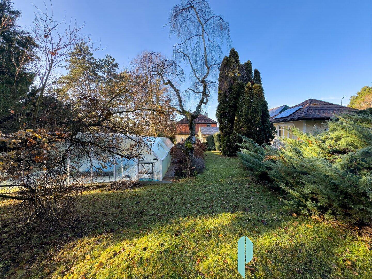 Großer Gartenbereich mit Gewächshaus und altem Baumbestand.