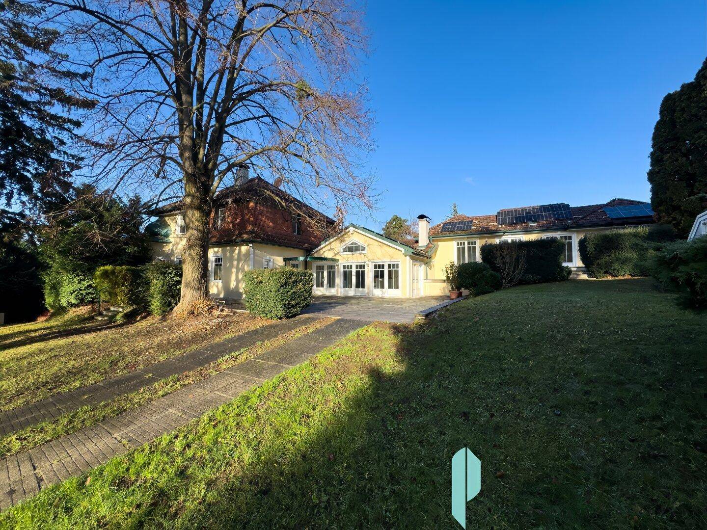Weitläufiger Gartenbereich mit großem Rasen und altem Baumbestand.