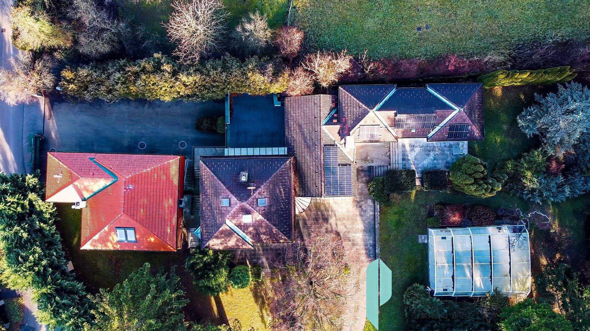 Draufsicht des weitläufigen Grundstücks mit Gebäuden, Garten, Pool und Gewächshaus.