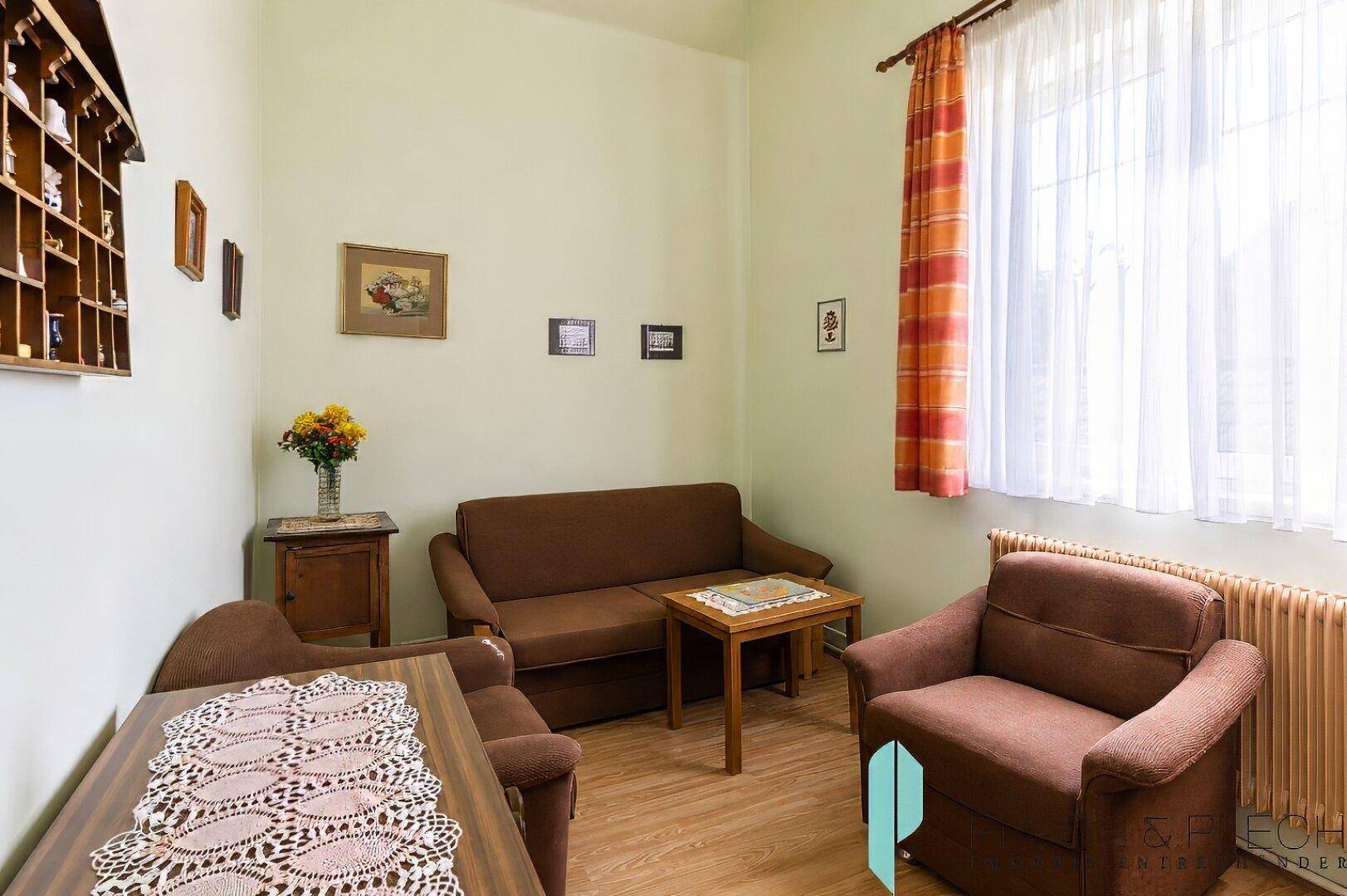 Gemütliches Wohnzimmer mit braunen Sofas, Holztisch und traditioneller Dekoration.