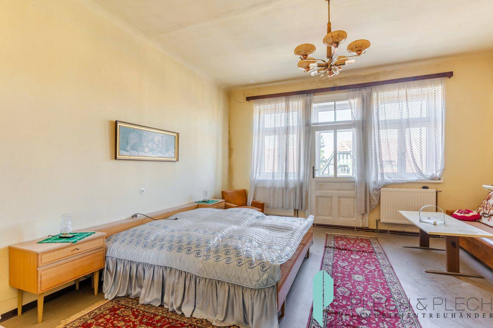 Helles Schlafzimmer mit Doppelbett, Nachttischen und Zugang zu einem Balkon.