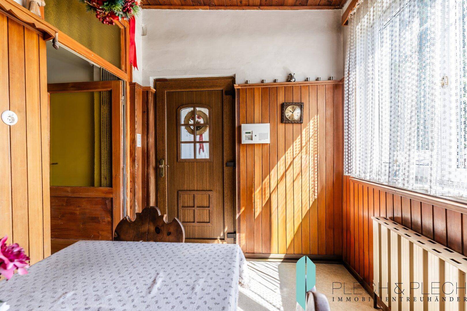 Heller Eingangsbereich mit Holzverkleidung, Fensterfront und traditioneller Dekoration.