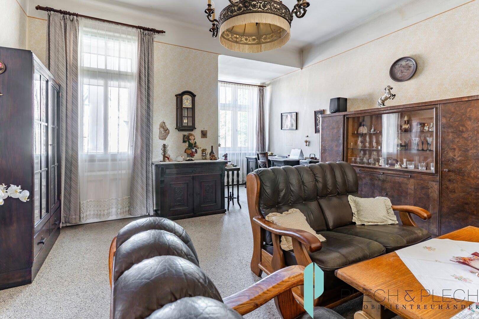 Klassisches Wohnzimmer mit Ledersofa, antiken Möbeln und hohen Decken.