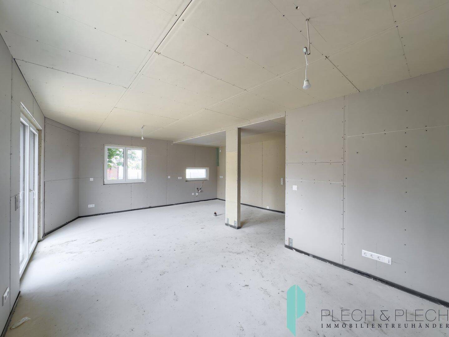 Heller Rohbau-Wohnraum mit großen Fenstern und viel Potenzial für individuelle Gestaltung.