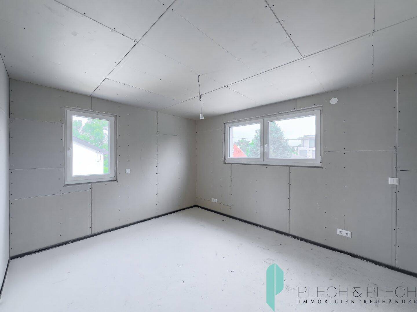 Rohbau-Zimmer mit zwei Fenstern, bereit für den Innenausbau und persönliche Einrichtung.