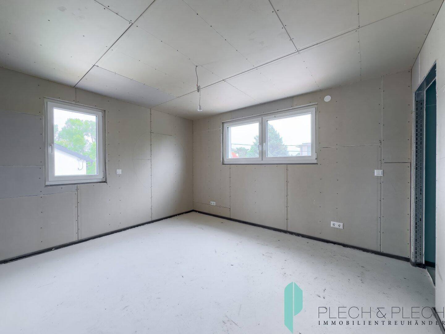 Helles Rohbau-Zimmer mit Fenstern, ideal für ein Schlafzimmer oder Arbeitszimmer.