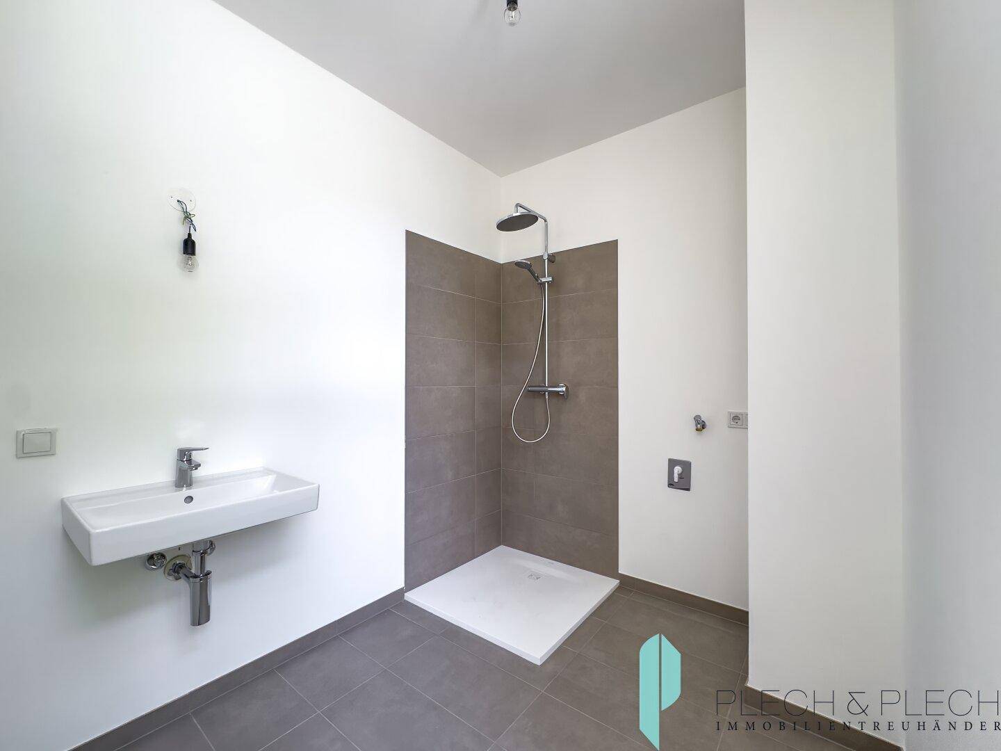 Zeitgemäßes Badezimmer mit ebenerdiger Dusche und Waschbecken, ausgestattet mit modernen Fliesen.
