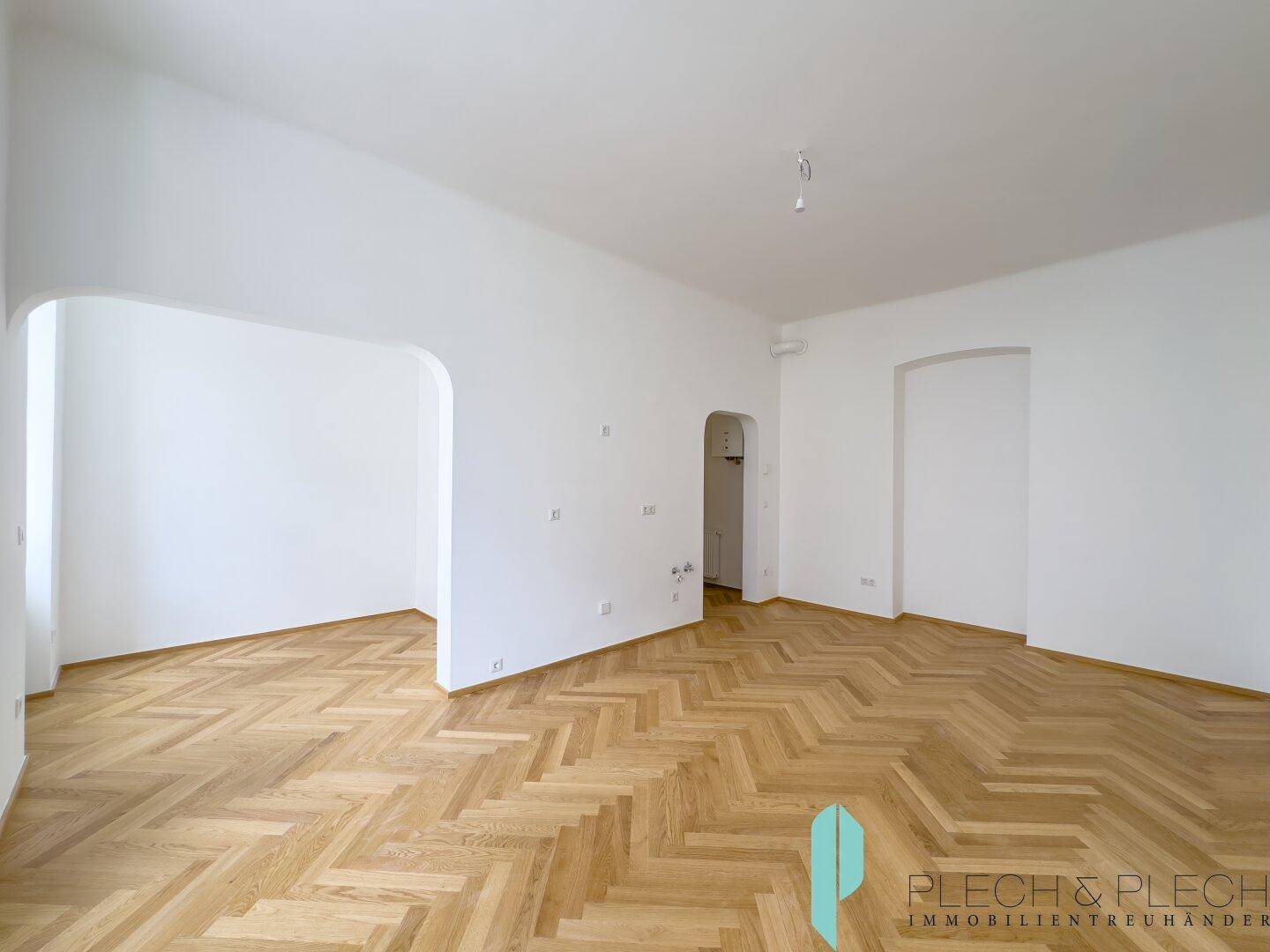 Geräumiges, helles Zimmer mit Fischgrätparkett und eleganten Rundbögen, bietet vielseitige Nutzungsmöglichkeiten.
