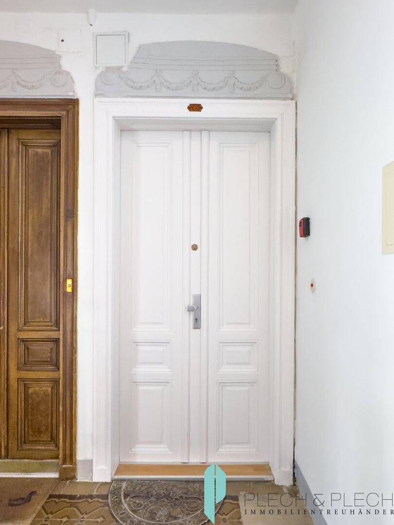 Elegante weiße Doppeltür mit Zierleisten und klassischem Design, als Wohnungseingang.