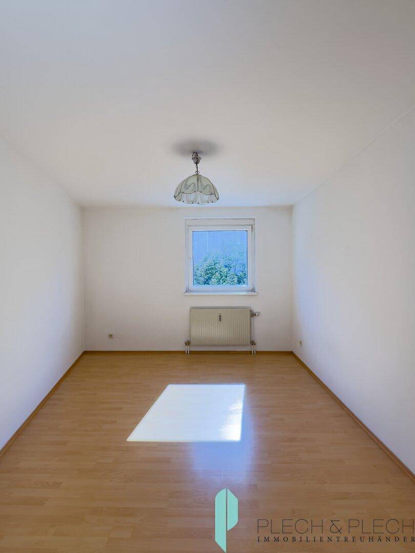 Freundliches Zimmer mit Parkettboden und einem Fenster, das den Raum mit Tageslicht erfüllt.