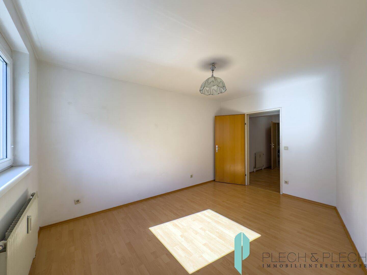Helles Zimmer mit Parkettboden und weiß gestrichenen Wänden, ideal als Schlaf- oder Arbeitszimmer.