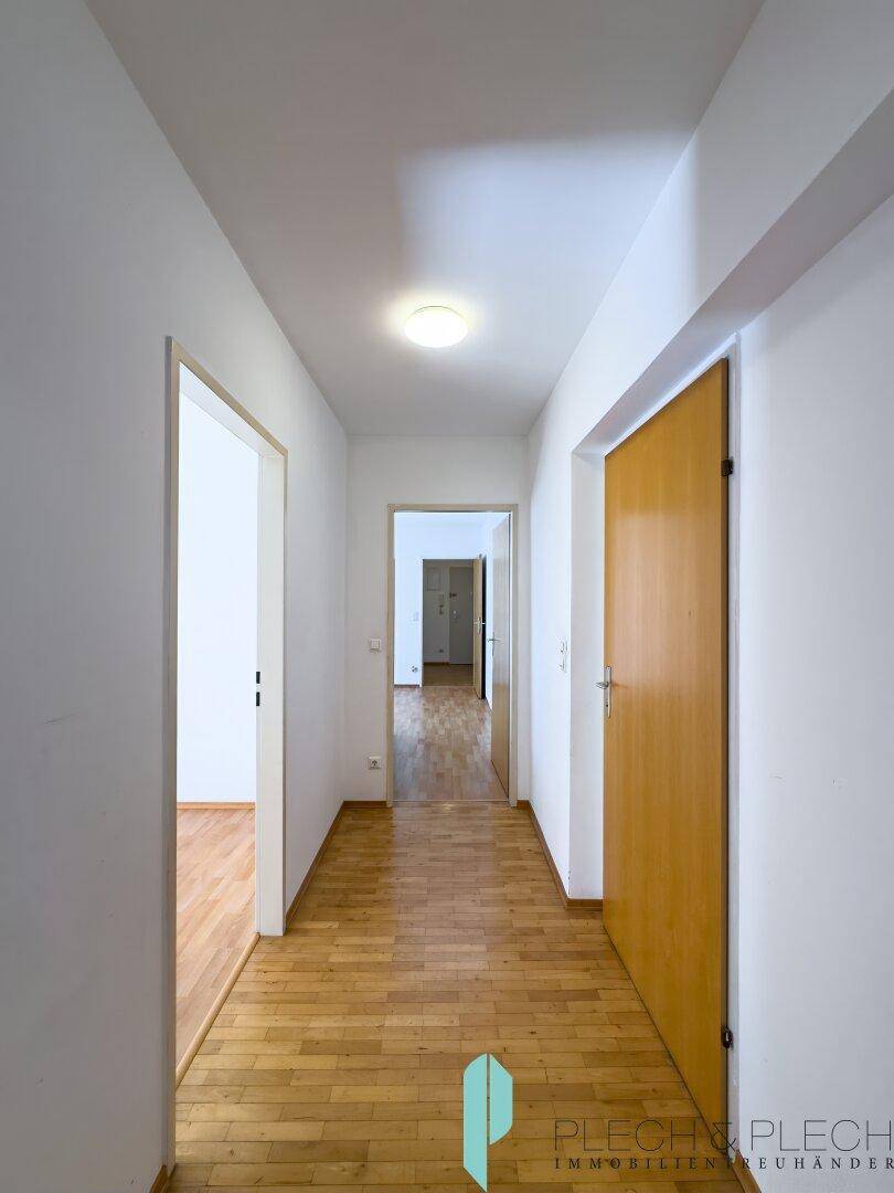 Heller Flur mit Parkettboden, der zu verschiedenen Zimmern der Wohnung führt.