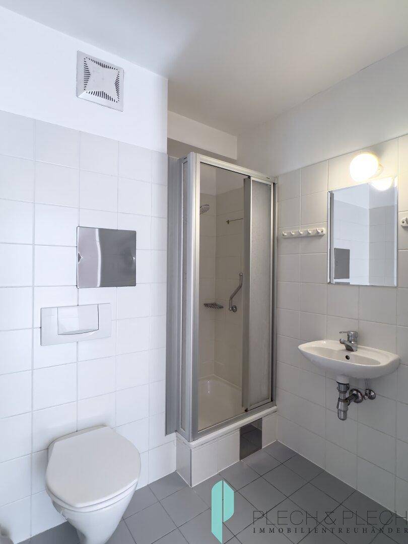 Modernes Badezimmer mit Duschkabine, WC und Waschbecken, komplett gefliest in hellen Farben.
