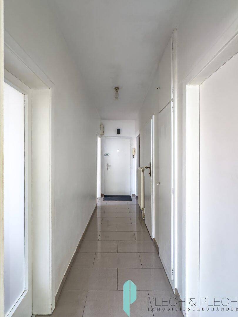 Heller Flur mit Fliesenboden und Blick auf die Eingangstür der Wohnung.