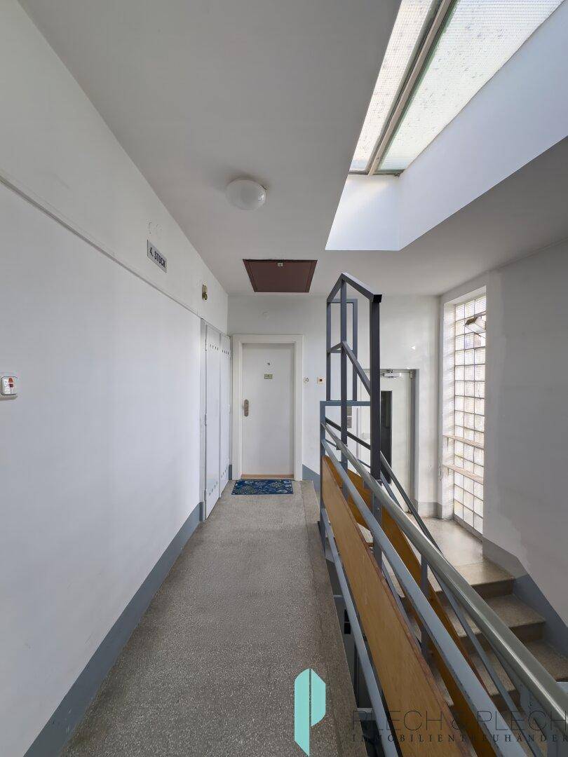 Langer Hausflur mit Treppenhaus, Oberlicht und Zugang zum Aufzug.