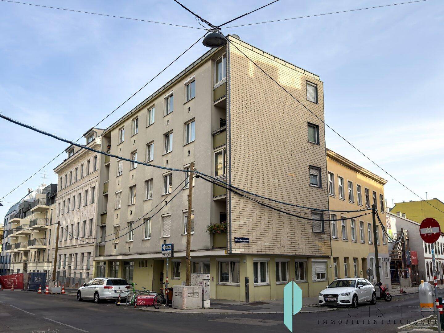 Eckgebäude an einer Straße mit mehreren Etagen und vielen Fenstern.